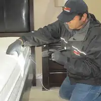Bed bug inspection technician checking a mattress and bed frame for signs of infestation in Orlando, FL