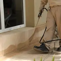 General pest control technician spraying exterior perimeter around a home in Orlando, FL