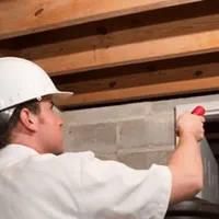 Termite inspection technician checking a basement wall and framing for termite activity in Orlando, FL