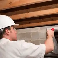 Termite inspection technician checking a basement wall and framing for termite activity in Orlando, FL